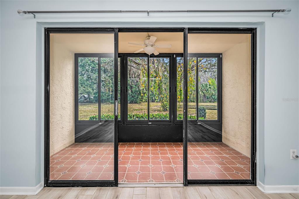 A sliding glass door opens to a screened-in porch with tiled flooring and a ceiling fan — 3232 LAKE PINE WAY E UNIT C1, TARPON SPRINGS, FL