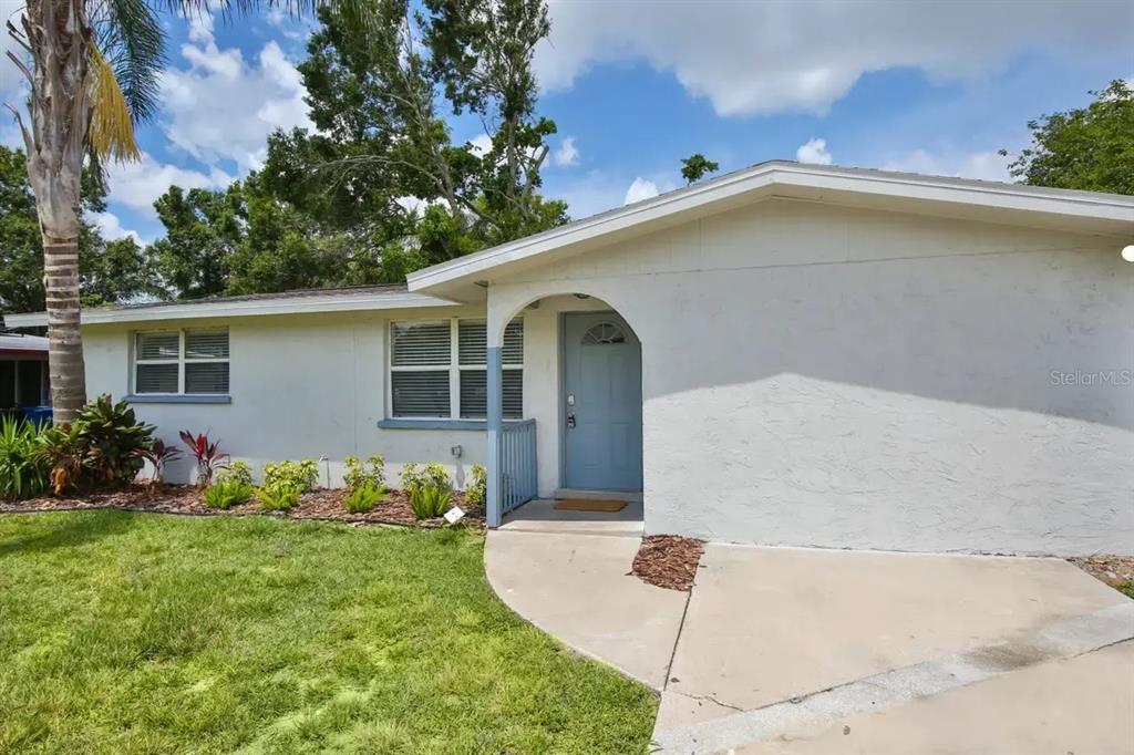 A single-story house with a light-colored stucco exterior, a blue front door, and a palm tree — 5622 S LOCKWOOD RIDGE ROAD, SARASOTA, FL