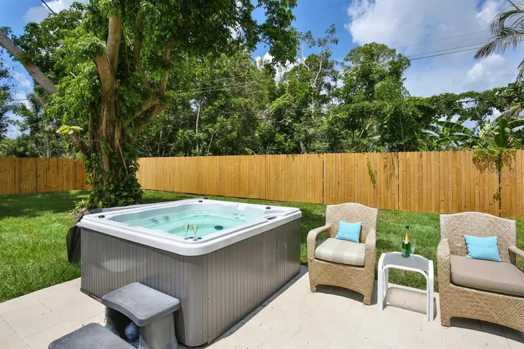 A hot tub sits on a patio next to two wicker chairs in a backyard — 5622 S LOCKWOOD RIDGE ROAD, SARASOTA, FL