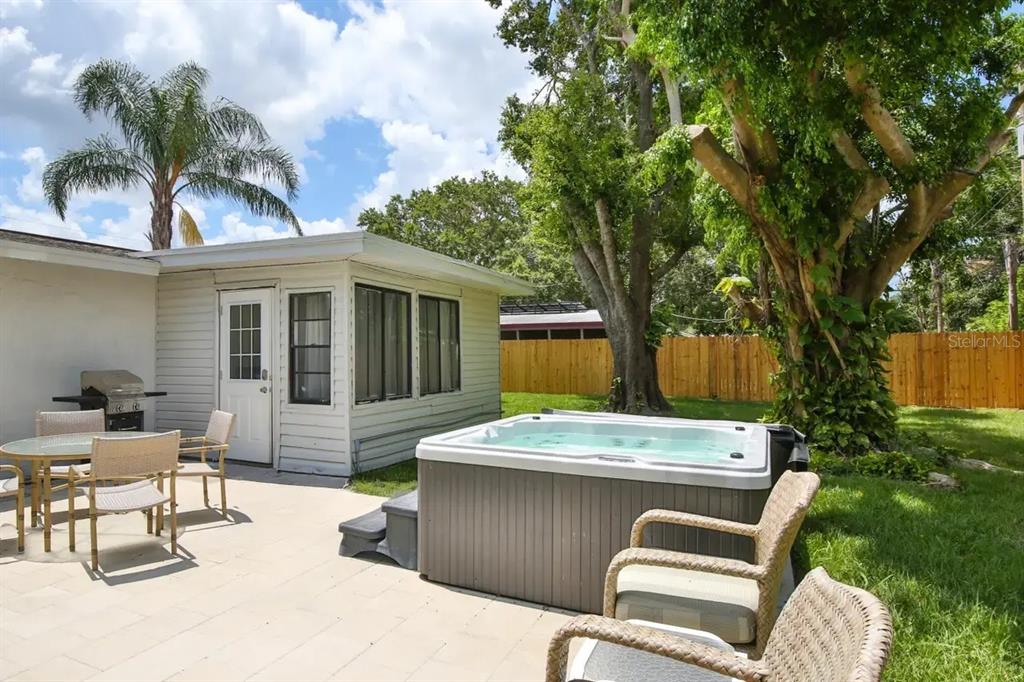A backyard patio features a hot tub, outdoor dining set, and a white exterior building — 5622 S LOCKWOOD RIDGE ROAD, SARASOTA, FL