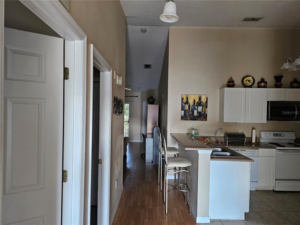 A view from a hallway looking into a kitchen with a breakfast bar and stools — 8815 GRAND PALMS CIRCLE UNIT B, KISSIMMEE, FL