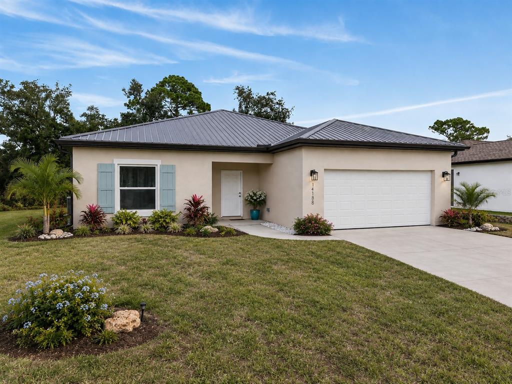 A single-story house with a metal roof, light-colored stucco, and a two-car garage — 14188 GABLES AVENUE, PORT CHARLOTTE, FL