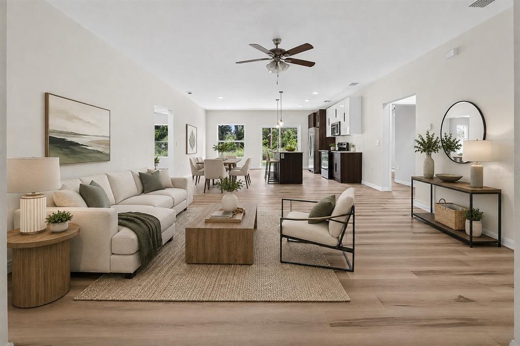 This is a virtually staged open-concept living room and kitchen with light wood-look flooring — 14188 GABLES AVENUE, PORT CHARLOTTE, FL