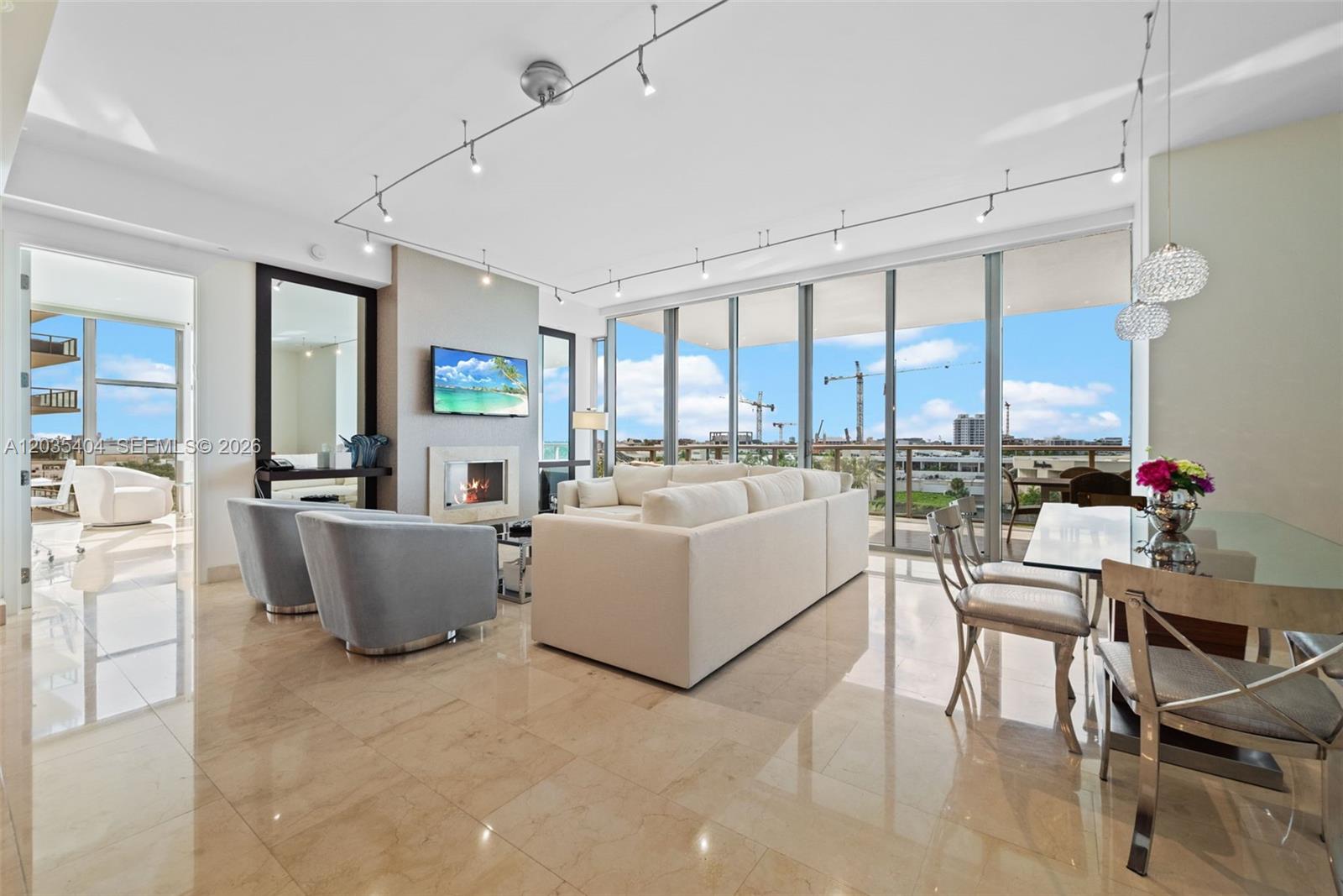 A modern living and dining room features marble floors, track lighting, and floor-to-ceiling windows — 9705 Collins Ave # 605N, Bal Harbour FL 33154, BAL HARBOUR, FL