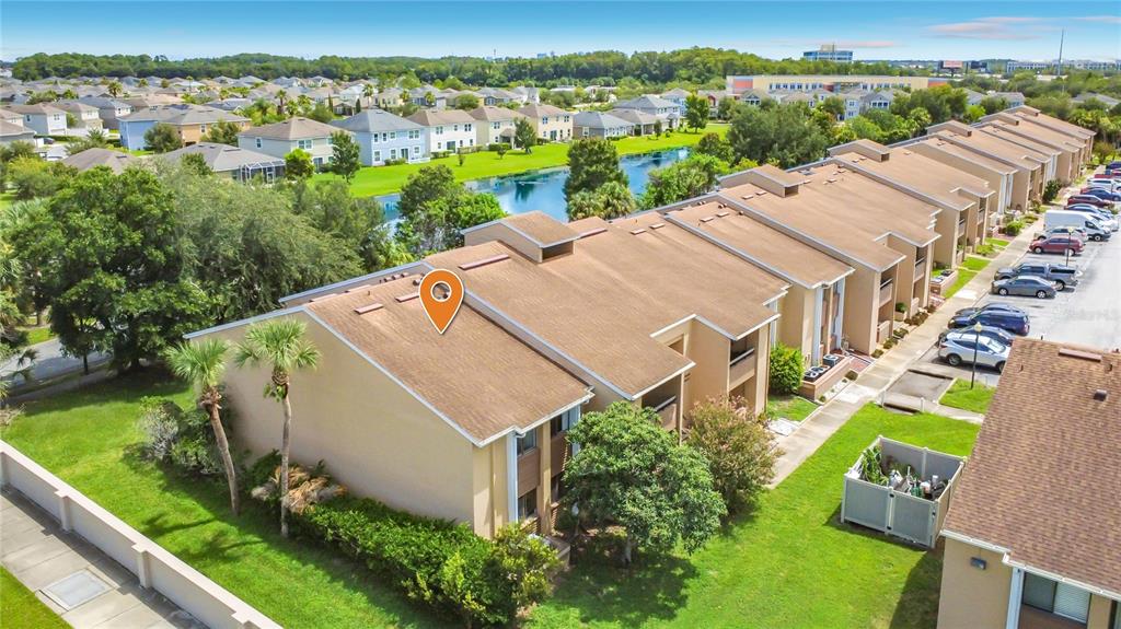 An aerial view of a multi-unit townhouse complex with a brown roof and green lawn — 5247 VINELAND ROAD UNIT 202, ORLANDO, FL