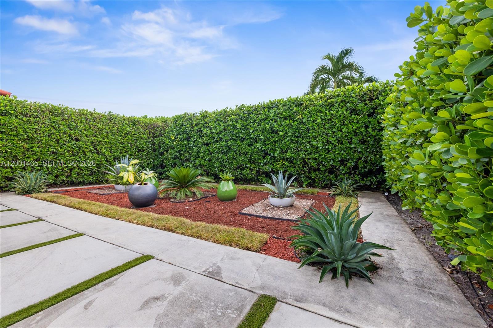 A landscaped garden features potted plants and succulents set within a mulched bed near hedges — 2121 Red Rd # 0, Coral Gables FL 33155, CORAL GABLES, FL