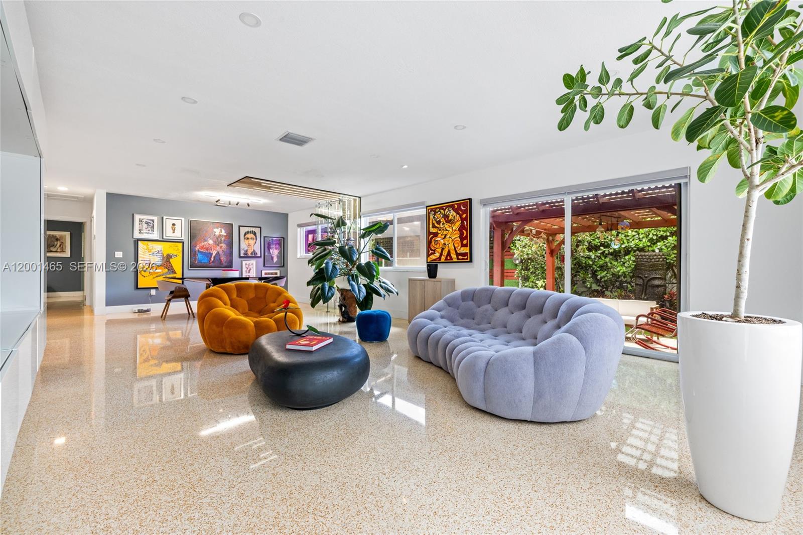 A modern living room features a grey tufted sofa, orange chair, and polished terrazzo floors — 2121 Red Rd # 0, Coral Gables FL 33155, CORAL GABLES, FL