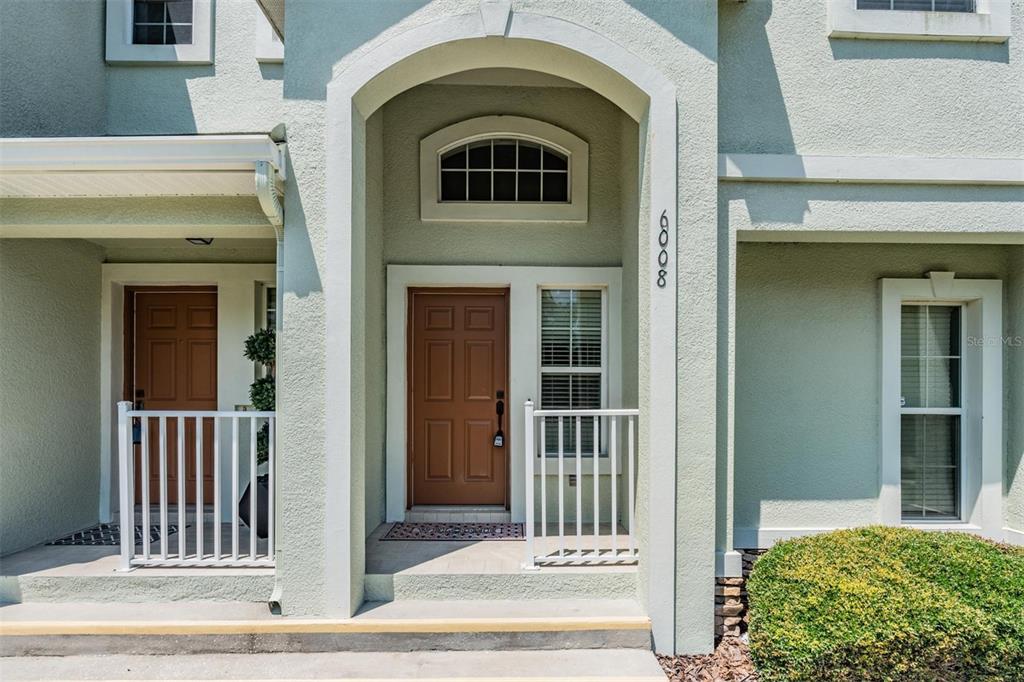 The exterior of a two-story home features a covered entryway with a brown front door — 6008 FISHHAWK CROSSING BOULEVARD UNIT 6008, LITHIA, FL
