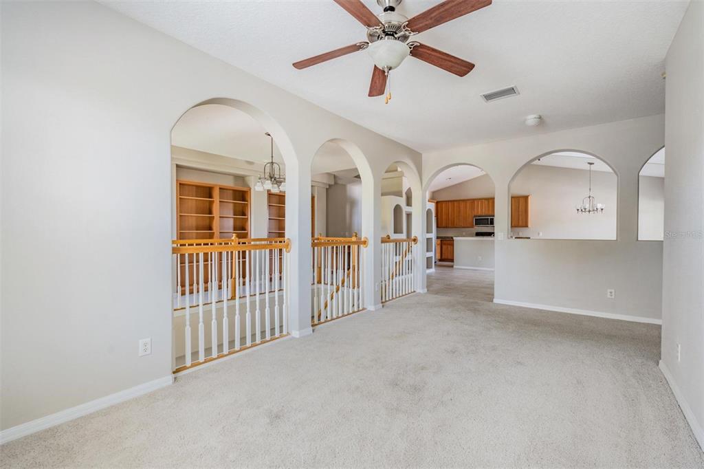 A carpeted room features arched openings, a ceiling fan, and a wooden staircase railing — 6008 FISHHAWK CROSSING BOULEVARD UNIT 6008, LITHIA, FL