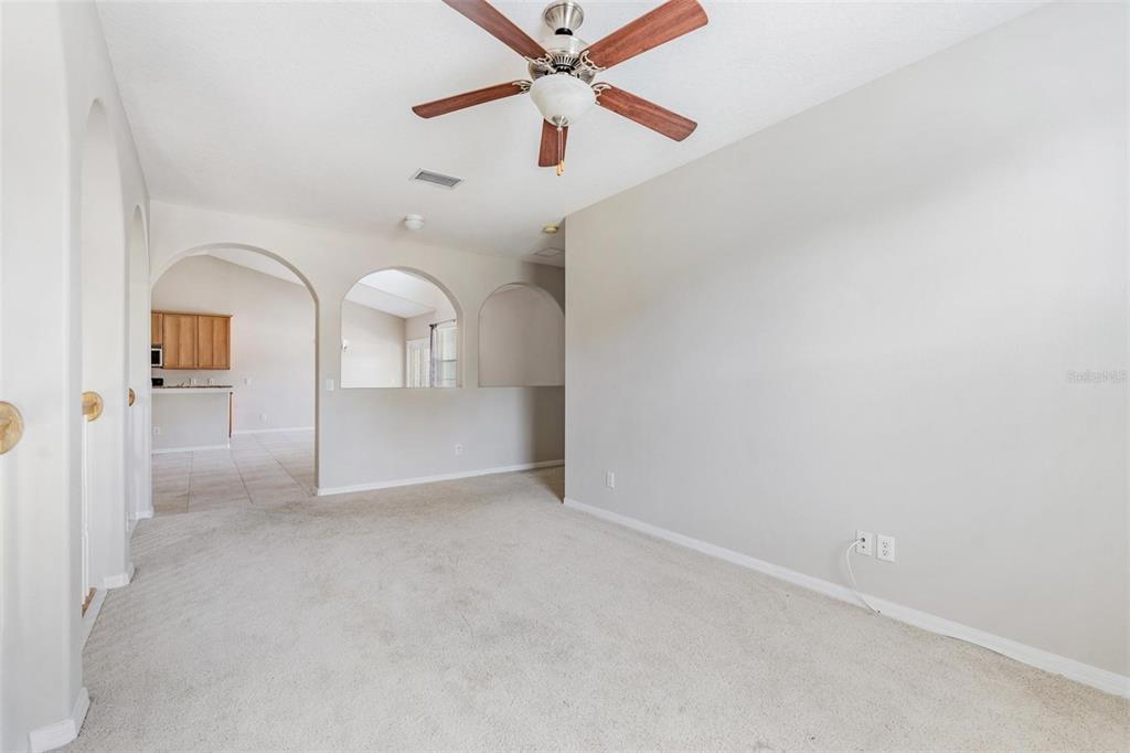 A carpeted living room features arched wall openings and a ceiling fan — 6008 FISHHAWK CROSSING BOULEVARD UNIT 6008, LITHIA, FL