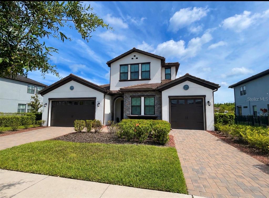 A two-story house features a three-car garage, stone accents, and a paved driveway — 6166 MARSH TRAIL DRIVE, ODESSA, FL