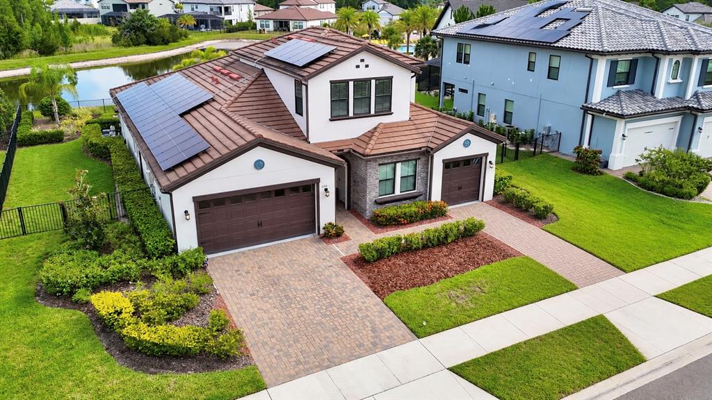 An aerial view of a two-story house with a tiled roof, solar panels, and driveway — 6166 MARSH TRAIL DRIVE, ODESSA, FL