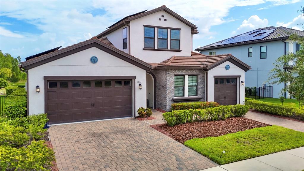 A two-story house with a stone facade, brown garage doors, and a paved driveway — 6166 MARSH TRAIL DRIVE, ODESSA, FL