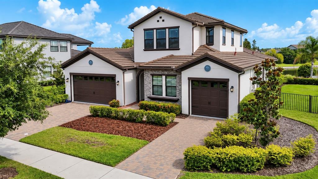 A two-story house with a brown tile roof, white stucco walls, and two garage doors — 6166 MARSH TRAIL DRIVE, ODESSA, FL