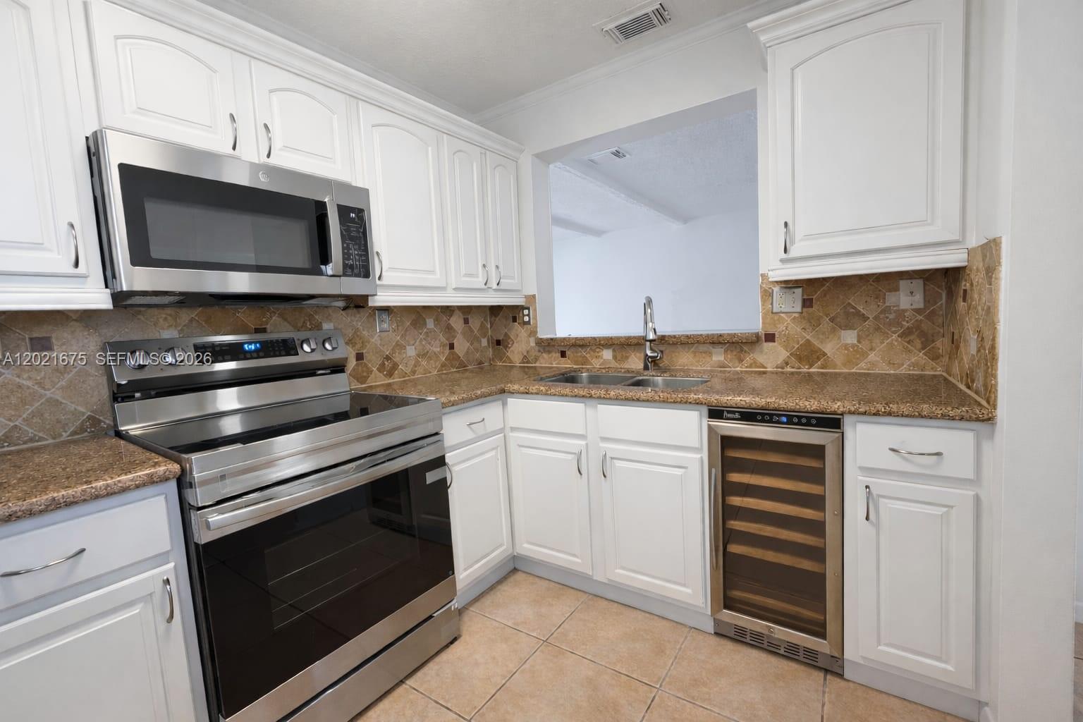 A kitchen features white cabinets, stainless steel appliances, granite countertops, and a tile backsplash — 15761 SW 137 ave # 202, Miami FL 33177, MIAMI, FL