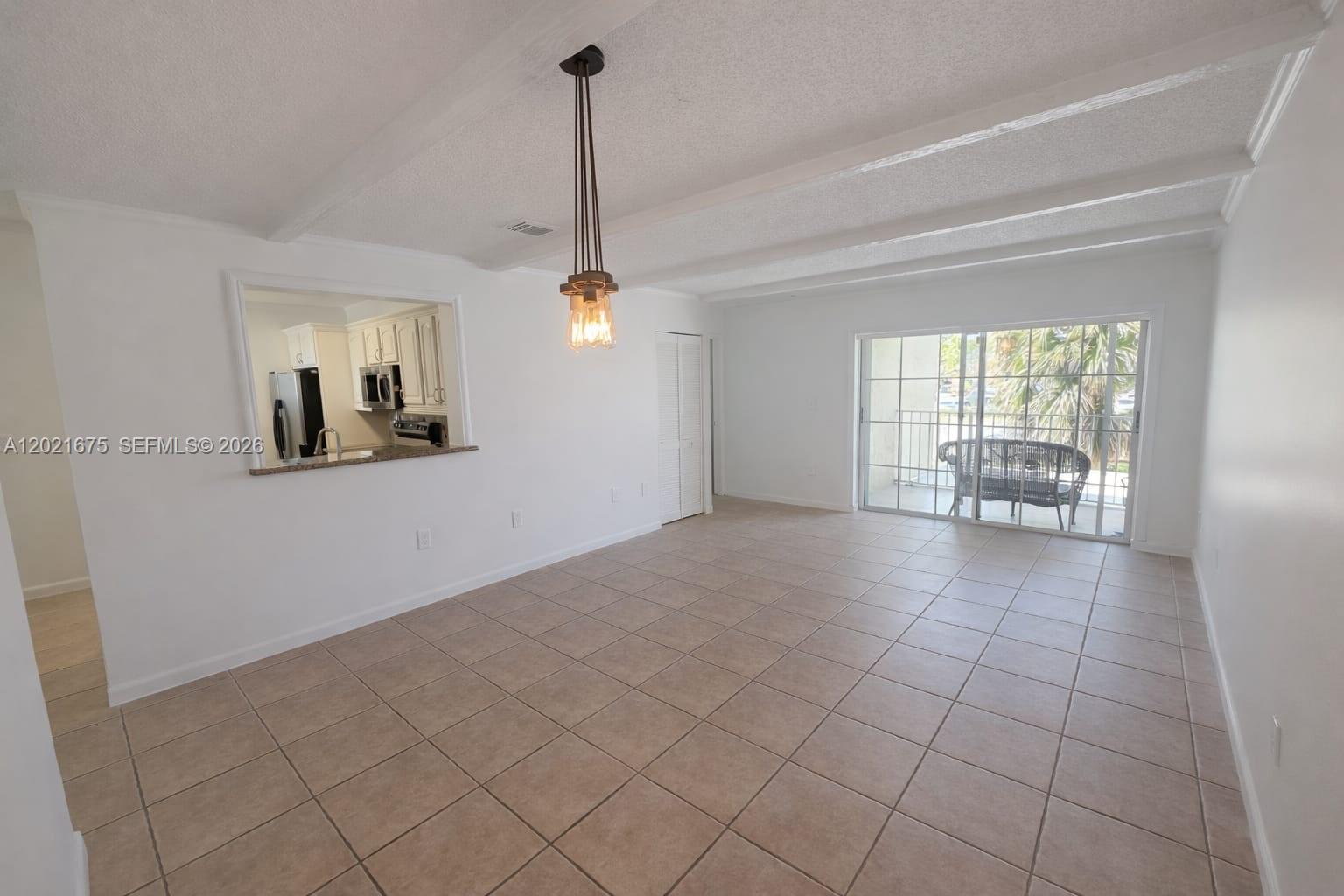 An open-concept dining area features tile flooring, a pass-through window to the kitchen, and sliding doors — 15761 SW 137 ave # 202, Miami FL 33177, MIAMI, FL