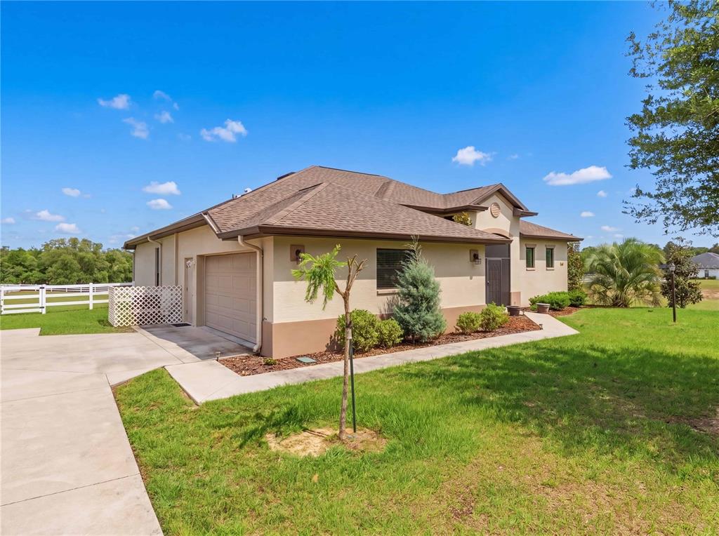 A single-story house with a tan stucco exterior, a brown roof, and an attached garage — 1381 N SPEND A BUCK DRIVE, HERNANDO, FL