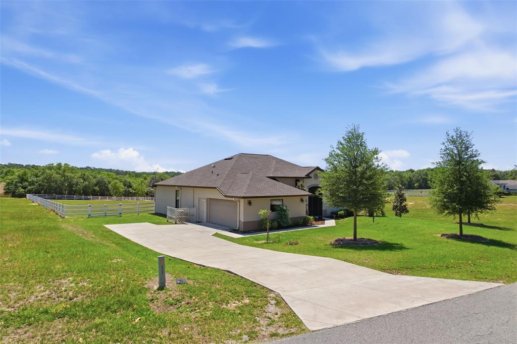 A single-story house with a concrete driveway and a white fence on a grassy lot — 1381 N SPEND A BUCK DRIVE, HERNANDO, FL
