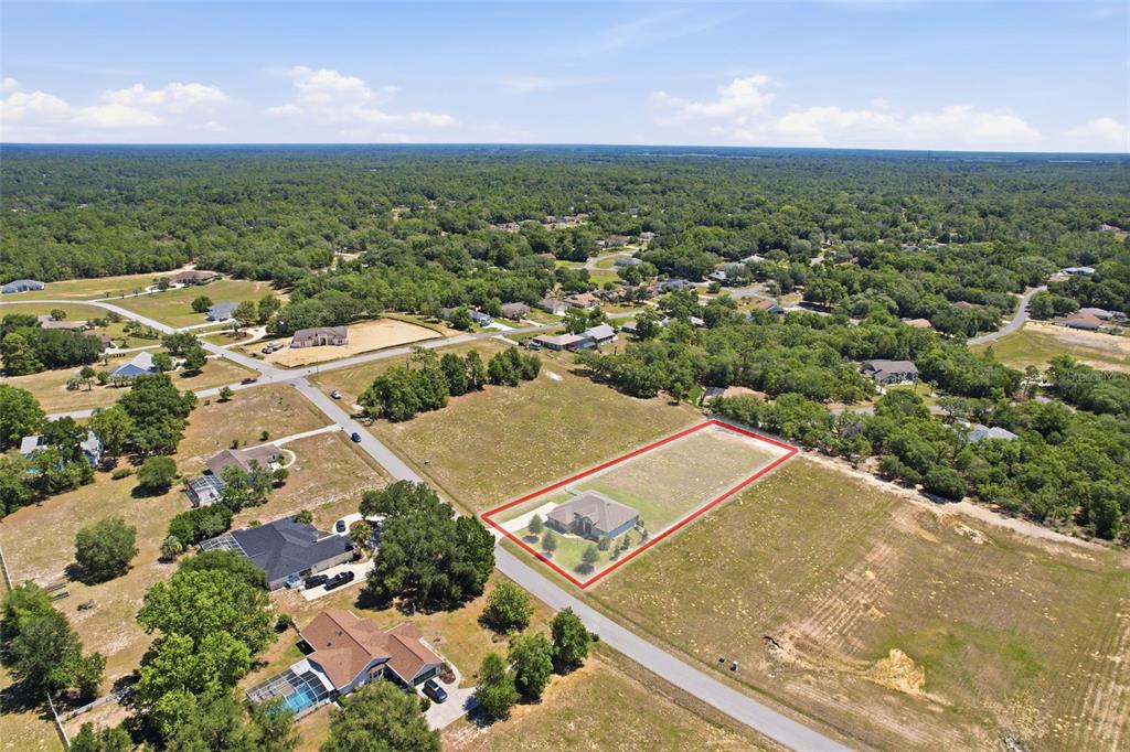 An aerial view shows a single-story house on a large, rectangular lot with red borders — 1381 N SPEND A BUCK DRIVE, HERNANDO, FL