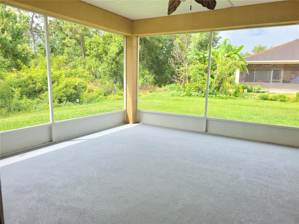 A screened-in porch with a gray concrete floor overlooks a grassy backyard and trees — 20722 GREAT LAUREL AVENUE, TAMPA, FL