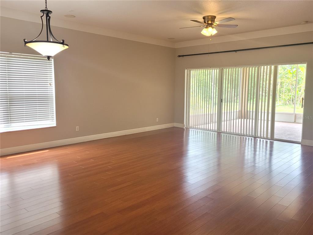 A spacious room with hardwood floors, a ceiling fan, a pendant light, and sliding doors — 20722 GREAT LAUREL AVENUE, TAMPA, FL
