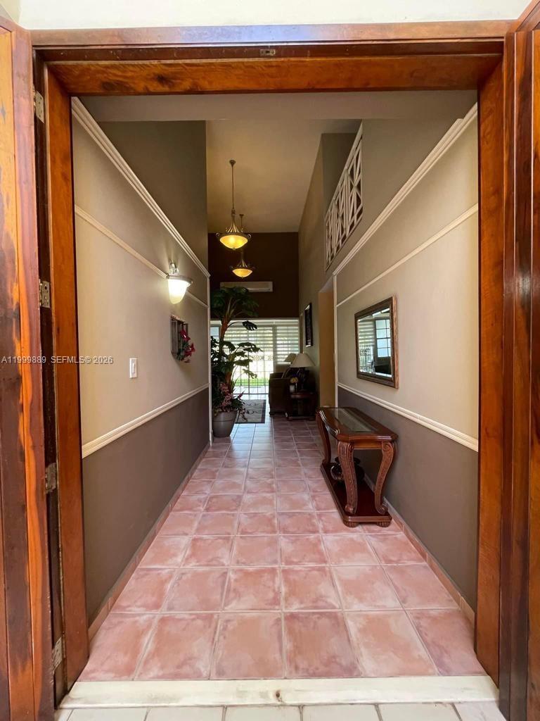 A tiled hallway leads toward a living area with high ceilings and a hanging light — 6690 Cond Royal Palm # G102, PR 00692, PR