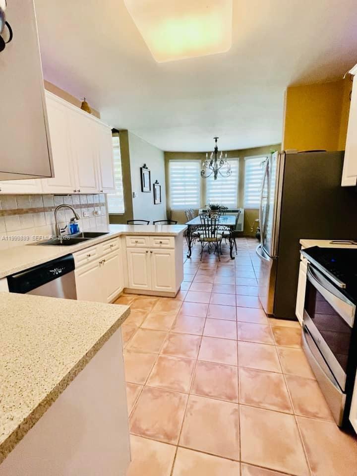 This kitchen features white cabinetry, light countertops, and a dining area with a chandelier — 6690 Cond Royal Palm # G102, PR 00692, PR