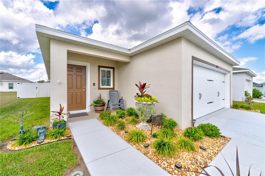 A single-story house exterior features a tan stucco facade, a brown front door, and a garage — 1609 FINNIGAN CIRCLE, HAINES CITY, FL