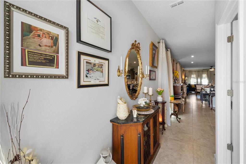 A hallway features a console table, wall art, a gold mirror, and tiled flooring — 1609 FINNIGAN CIRCLE, HAINES CITY, FL