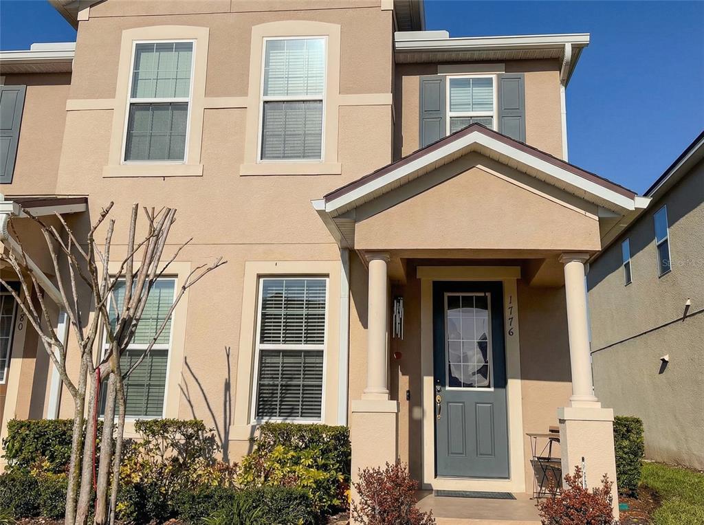 The exterior of a two-story tan house features a covered front porch with white columns — 1776 FULFILLMENT DRIVE, KISSIMMEE, FL