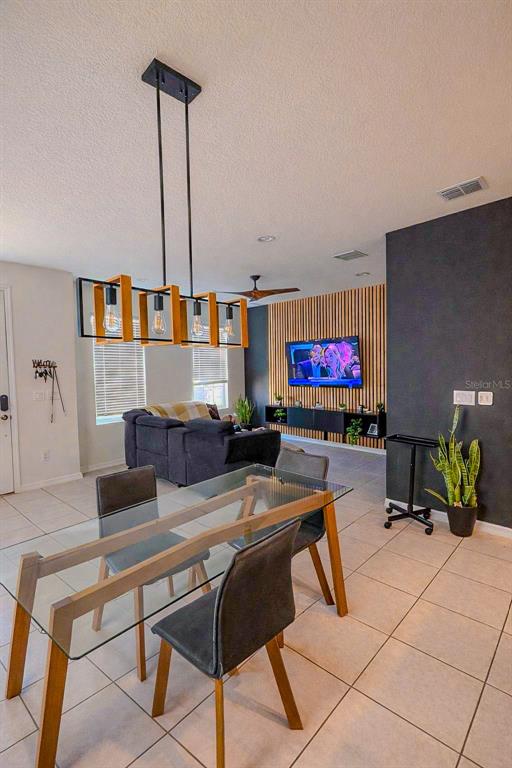 A dining area with a glass table and pendant light overlooks a living room — 1776 FULFILLMENT DRIVE, KISSIMMEE, FL