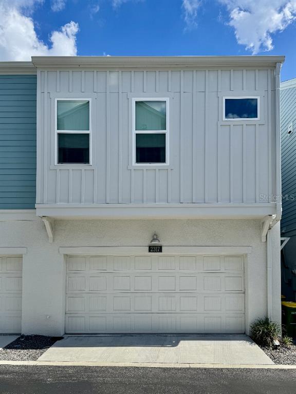 The exterior of a two-story townhouse features a white garage and vertical siding above — 2317 LINDSTROM STREET, SARASOTA, FL