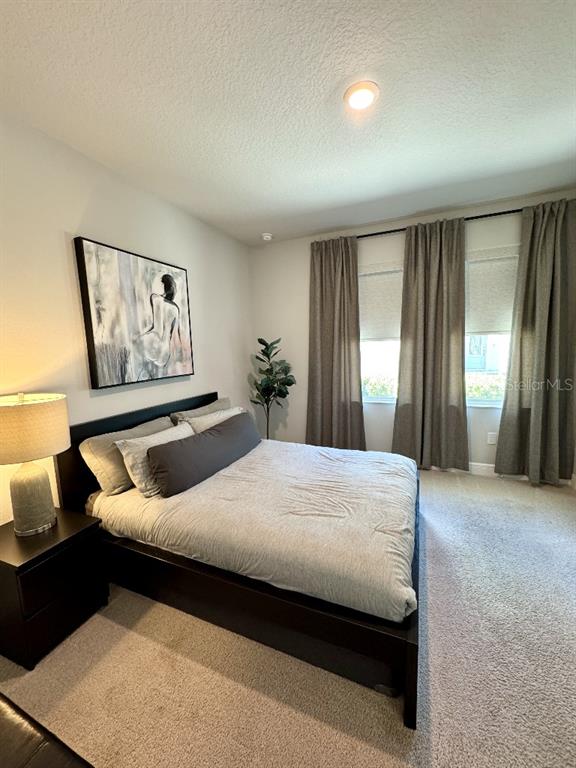 A bedroom features a dark bed frame, gray bedding, a bedside lamp, and floor-length curtains — 2317 LINDSTROM STREET, SARASOTA, FL