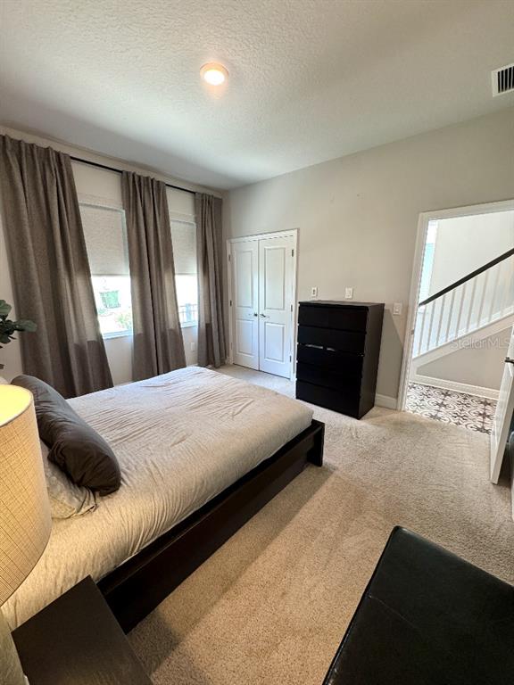 A bedroom features a bed, a black dresser, and a doorway leading to stairs — 2317 LINDSTROM STREET, SARASOTA, FL