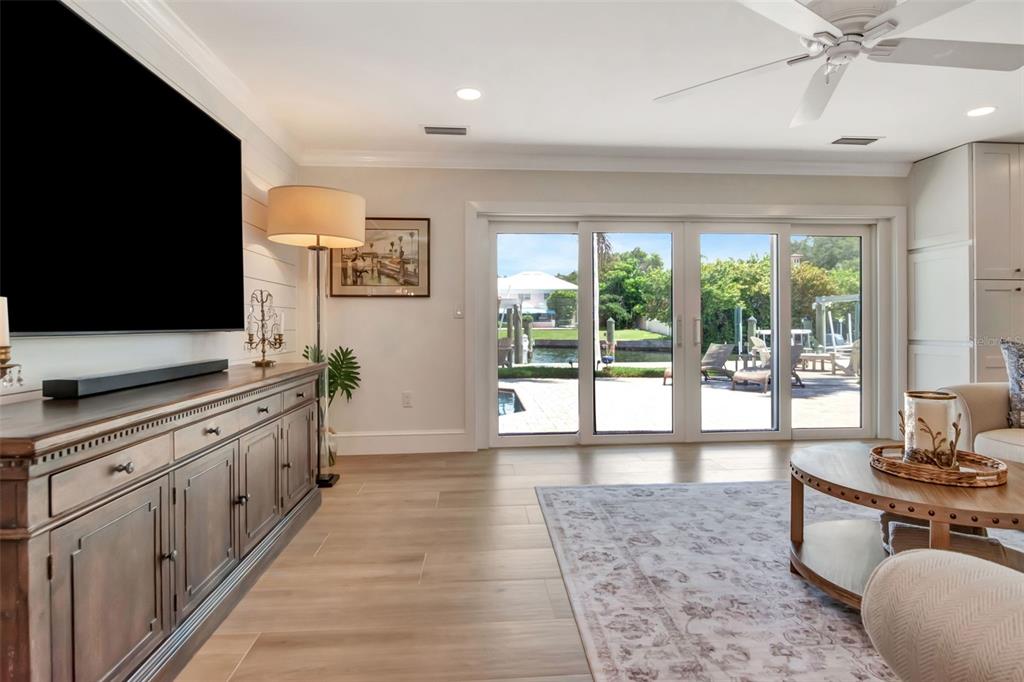 A living room features a large television, wooden media console, and sliding glass doors to a patio — 4927 W MELROSE AVENUE N, TAMPA, FL