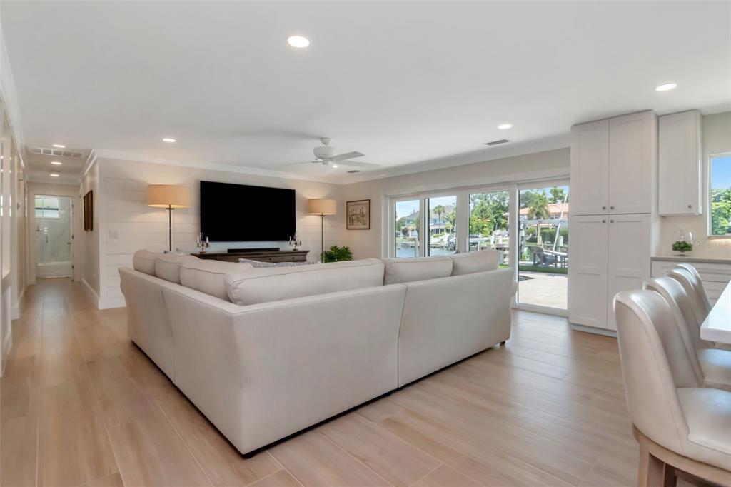A spacious living room features a large sectional sofa, light wood flooring, and sliding glass doors — 4927 W MELROSE AVENUE N, TAMPA, FL