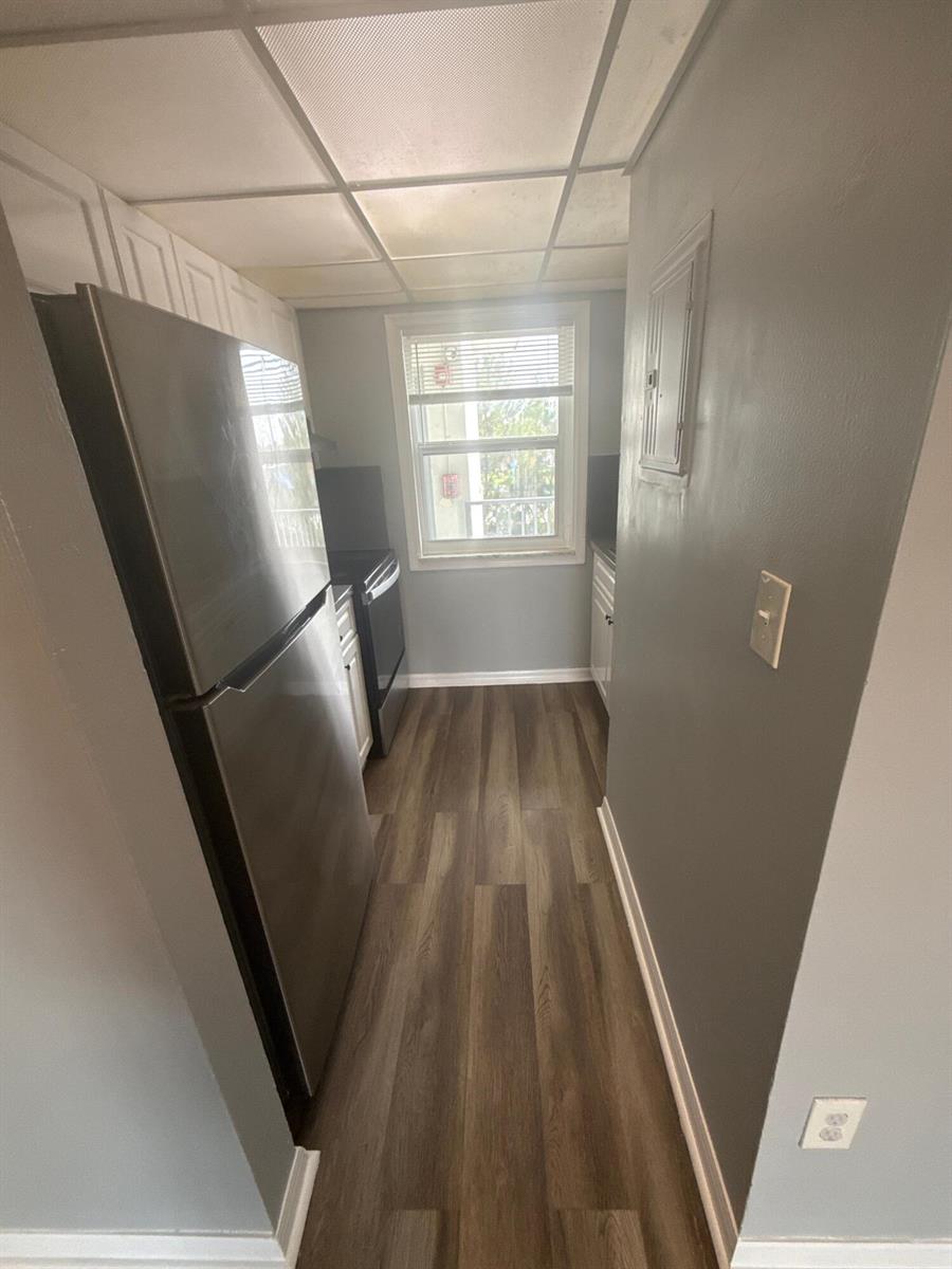 A narrow galley kitchen features stainless steel appliances, gray walls, and wood-look vinyl flooring — 2605 NW 135th Street # 309, Opa-Locka FL 33167, OPA-LOCKA, FL