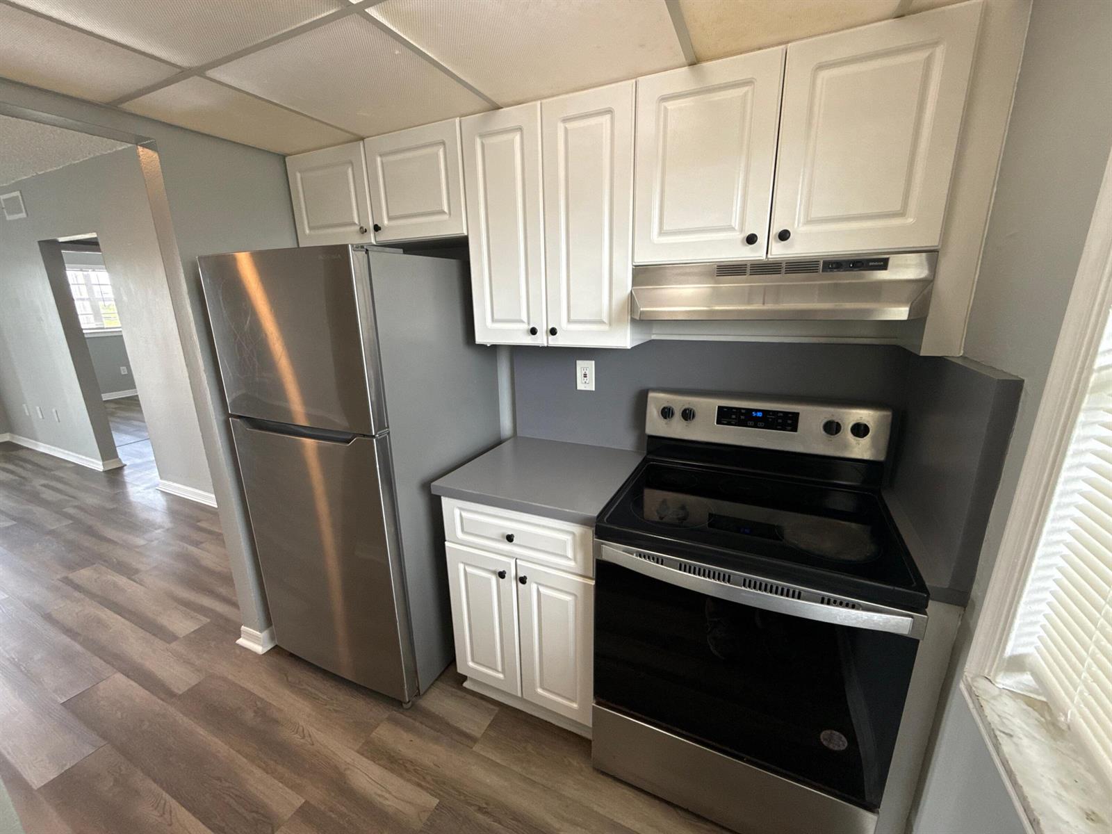 A kitchen features white cabinets, stainless steel appliances, gray countertops, and wood-look flooring — 2605 NW 135th Street # 309, Opa-Locka FL 33167, OPA-LOCKA, FL