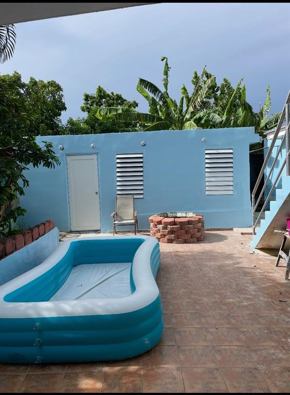 An outdoor patio features a blue inflatable pool, a brick fire pit, and a chair — Lot 3 CALLE 3, GUANICA, PR