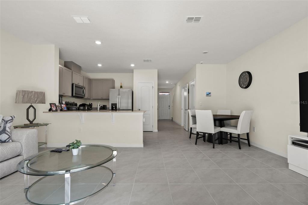 An open-concept living area features a kitchen with gray cabinets, tile floors, and dining space — 2722 PUFFIN PLACE, DAVENPORT, FL