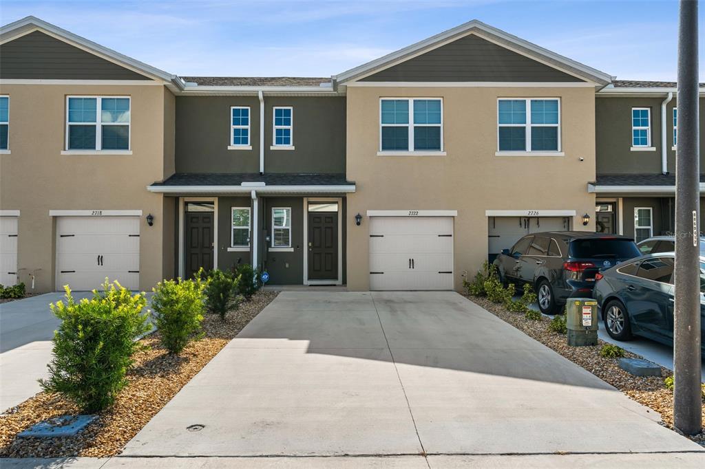 The exterior view shows a row of attached townhomes with garages and concrete driveways — 2722 PUFFIN PLACE, DAVENPORT, FL
