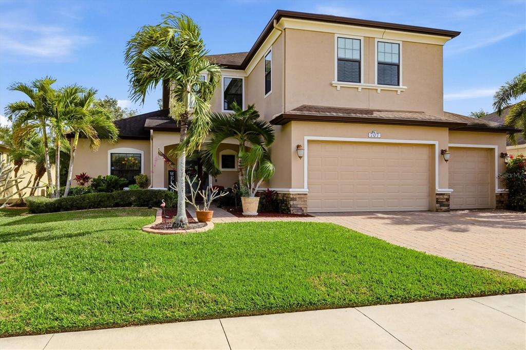 A two-story suburban house with a tan stucco exterior, a paved driveway, and palm trees — 707 DOGWOOD RUN, BRADENTON, FL