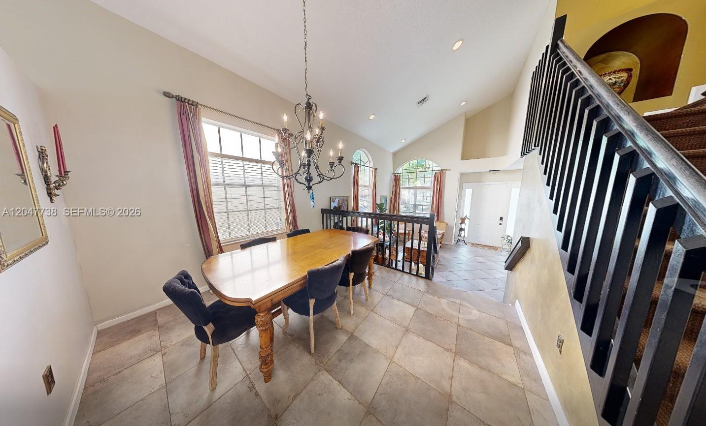 A dining area features a wooden table, dark chairs, a chandelier, and a staircase — 9640 Wyeth Ct, Wellington FL 33414, WELLINGTON, FL