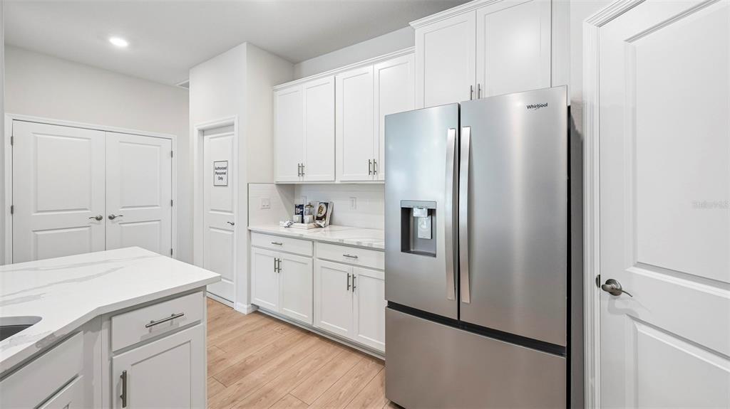 A kitchen features white cabinets, stainless steel appliances, and a marble-topped island — 18339 TAVERNSIDE TRAIL, LAKEWOOD RANCH, FL