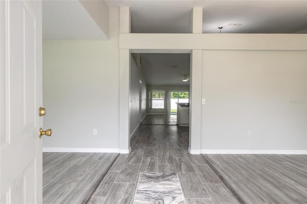 An entryway leads into a living area with gray wood-look tile flooring and neutral walls — 28 PILLORY LANE, PALM COAST, FL