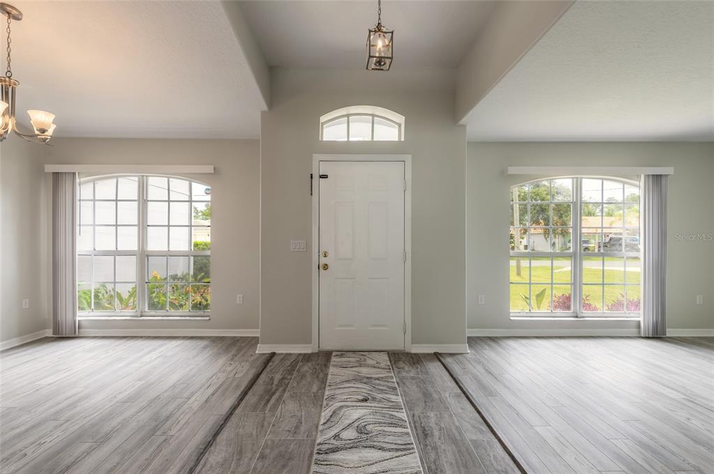 An entryway features light wood-look flooring, a white front door, and two large arched windows — 28 PILLORY LANE, PALM COAST, FL