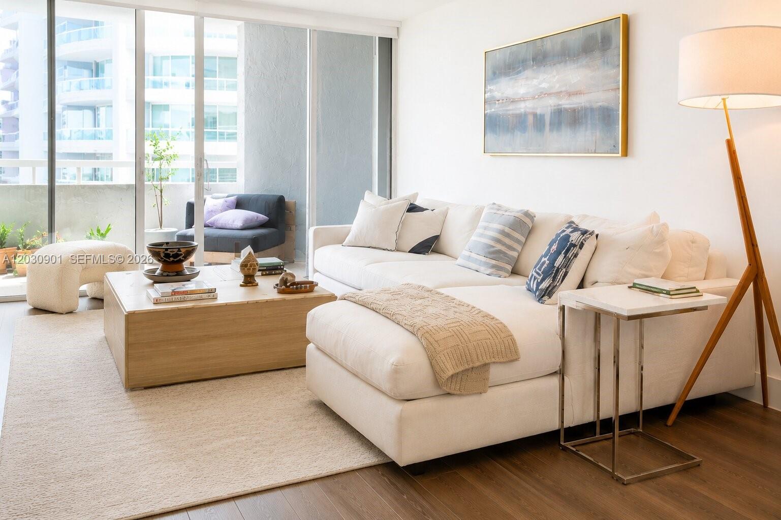 A bright living room features a white sectional sofa, wooden coffee table, and balcony access — 1627 Brickell Ave # 1005, Miami FL 33129, MIAMI, FL
