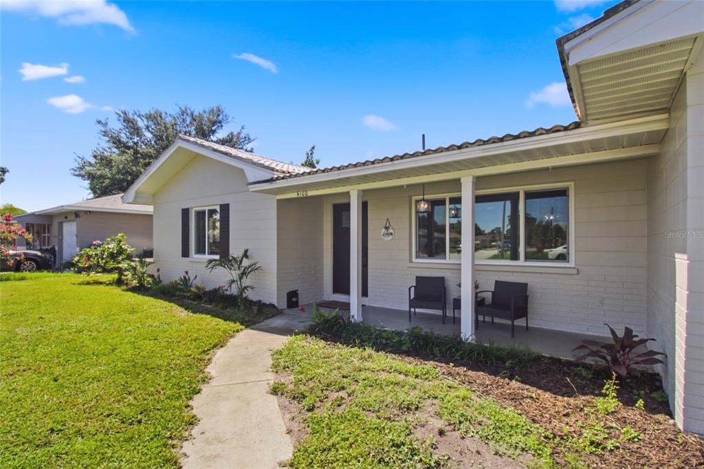 A single-story house with a light-colored brick exterior, a covered front porch, and a walkway — 4100 18TH AVENUE N, ST PETERSBURG, FL