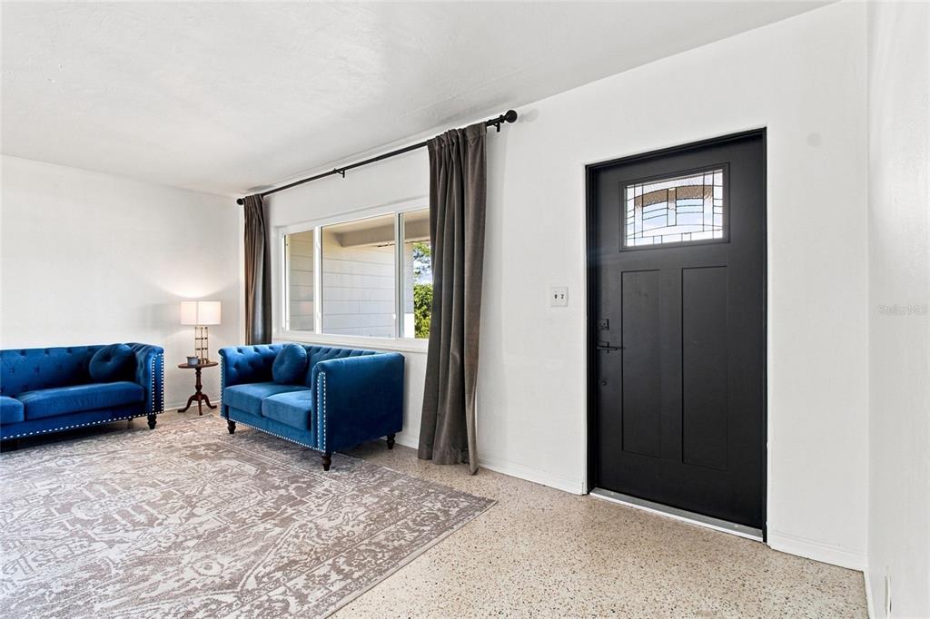 A living room features two blue tufted sofas, a patterned rug, and a black door — 4100 18TH AVENUE N, ST PETERSBURG, FL
