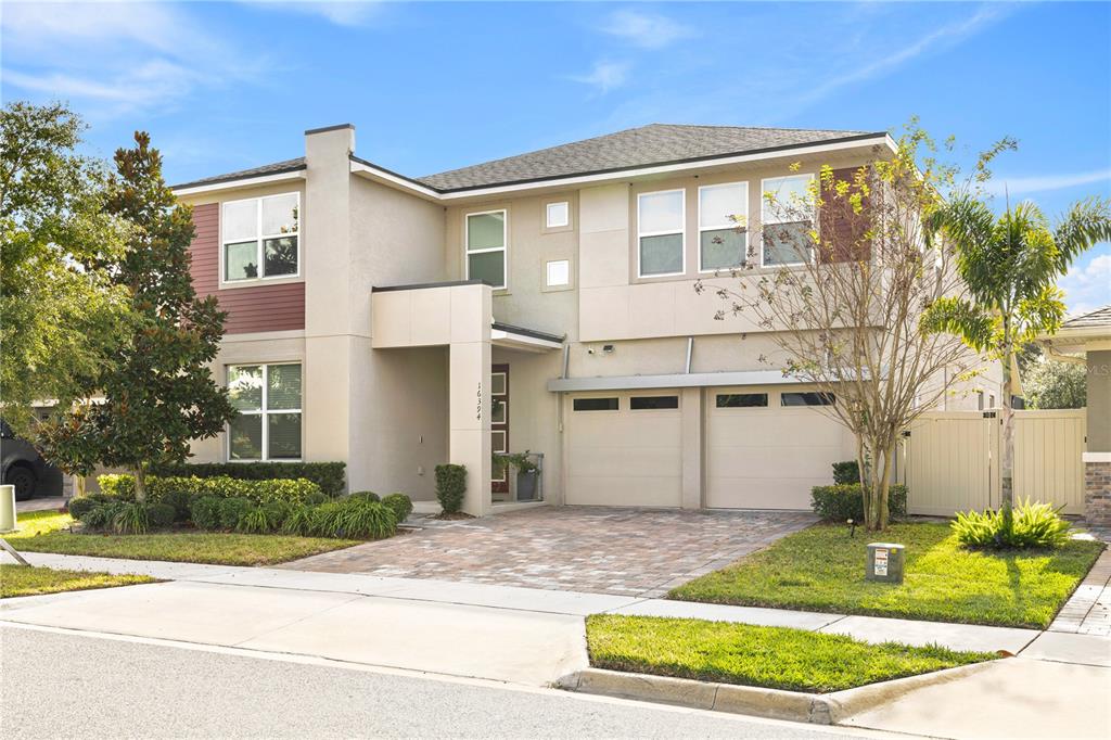 A two-story house with a beige stucco exterior, a two-car garage, and a paved driveway — 16394 TALIESIN STREET, WINTER GARDEN, FL